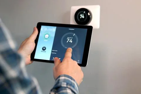 Man is Adjusting a temperature using a tablet with smart home app in room Stock Photos