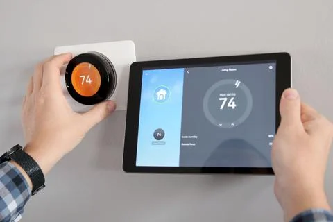 Man is Adjusting a  temperature using a tablet with a smart home app Stock Photos