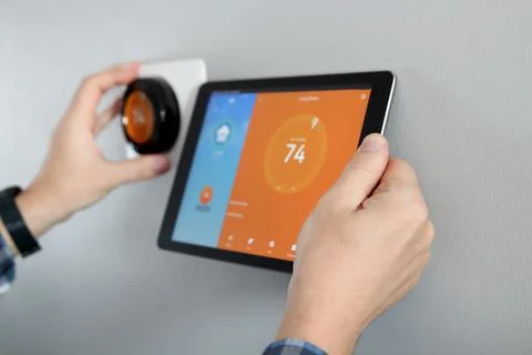 Man is Adjusting a  temperature using a tablet with a smart home app Stock Photos
