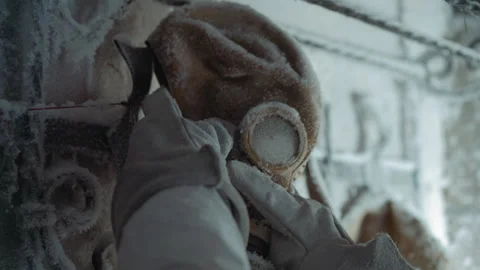 Man adjusting thermal gas mask amidst winter debris. Worker in insulated Stock Footage 346470751