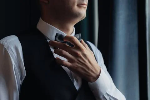 Man adjusts bow tie with gentle, precise touch Foto stock