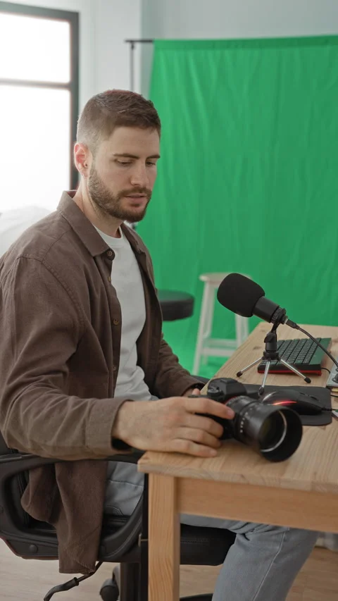 Man adjusts camera with both hands beside a microphone and computer at a st.. Stock Footage 347816813