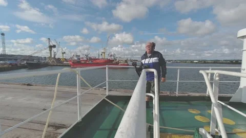 Man adjusts camera tripod on deck against cargo ships Video stock 147171770