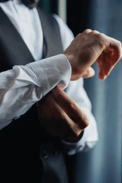 Man adjusts cuff of crisp white shirt Fotos Stock