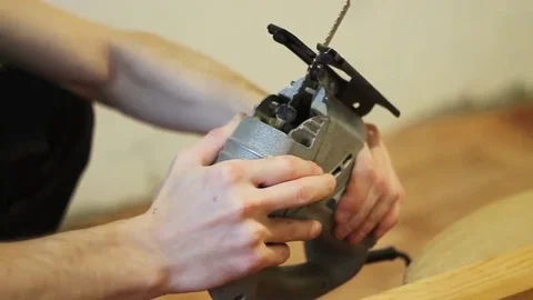 Man adjusts electric jigsaw Stock Footage 69214573