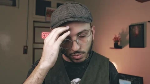 Man Adjusts Glasses in Cozy Studio with ON AIR Neon, Close-Up Stock Footage 318593940