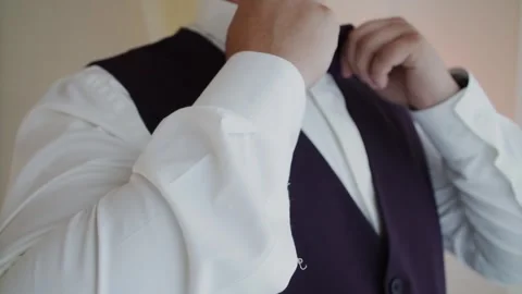 A man adjusts his bow tie near a window Video stock 329250163