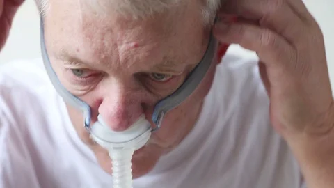 Man adjusts his CPAP breathing treatment device Stock Footage 90672011