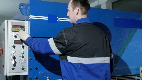 Man adjusts operation of the machine for cutting sheet metal on a large Video stock 71655180