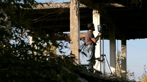 Man adjusts the retro camera in ruins Stock Footage 71824882