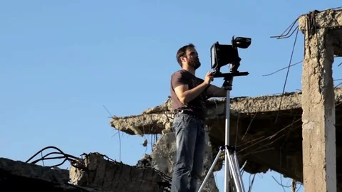 Man adjusts the retro camera in ruins Stock Footage 71824976