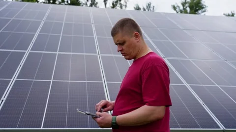 Man adjusts solar panels using tablet modern renewable energy technology Stock Footage 317153735