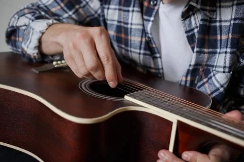 A man adjusts the strings on his guitar Stock Photos