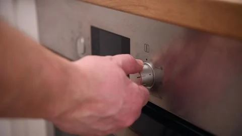 Man adjusts temperature and sets operating mode on modern oven in kitchen. Stock Footage 302279852