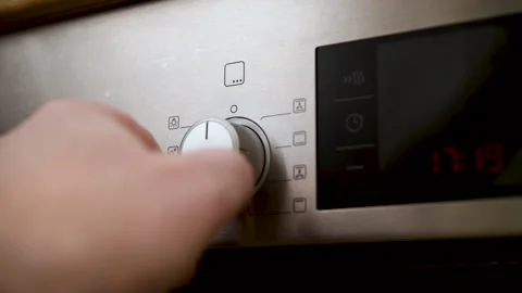 Man adjusts temperature and sets operating mode on modern oven in kitchen. Stock Footage 302835866