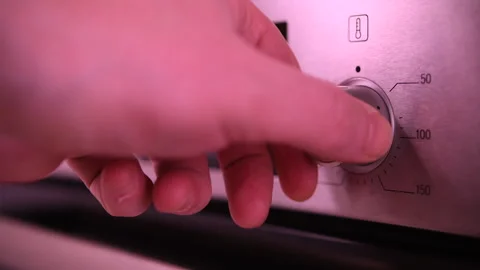 Man adjusts temperature and sets operating mode on modern oven in kitchen. Stock Footage 310882158