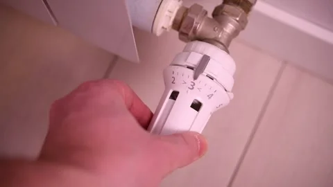 A man adjusts the temperature on a heating radiator in an apartment. Video stock 302540645