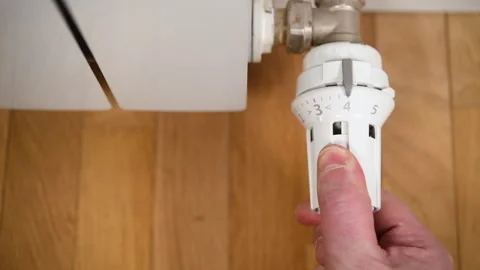 A man adjusts the temperature on a heating radiator in an apartment. Stock Footage 302722942