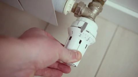 A man adjusts the temperature on a heating radiator in an apartment. Stock Footage 311049011
