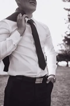 Man adjusts tie, smiling softly Foto stock