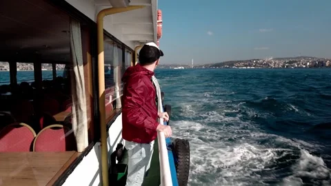 A man admires the city views from the deck of a boat in Istanbul, Türkiye Stock Footage 281643256