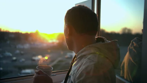 Man a admires the view while standing at the open window with a mug of hot tea Stock Footage 131034739