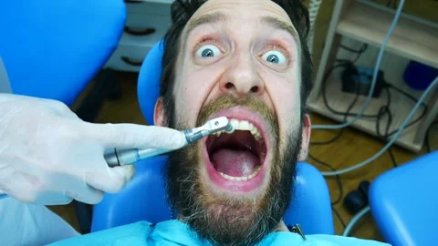 A man is afraid of professional teeth brushin and screams sitting at the dentist Vidéo 156640545