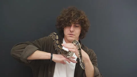 A man is afraid of a snake that crawls on his hand, a confused young man is in a Video stock 158668634