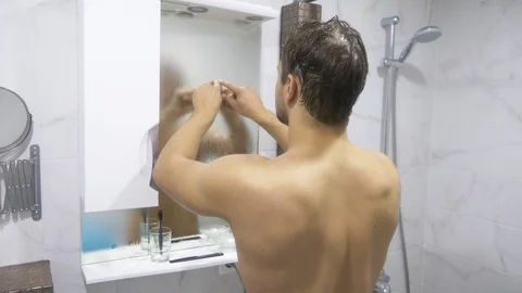Man after shower in the bathroom. He draws a heart on the mirror. Stock Footage 90092791