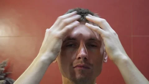 A man after taking a shower dries and styles his hair in a bathroom. Stock Footage 317751245
