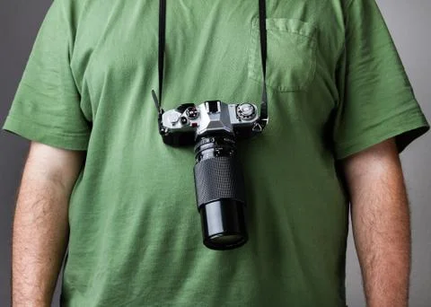 Man against gray background with camera strapped to him Stock Photos