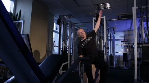 A man of the age performs joint gymnastics in the gym.Raising the arm vertically Stock Footage 115203131