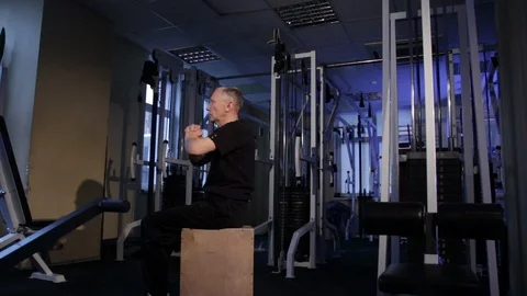 A man of the age performs joint gymnastics for the elbows and back in the gym Stock Footage 115204385