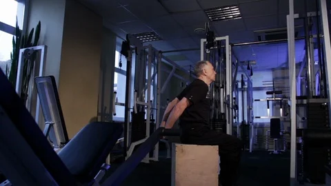 A man of the age performs joint gymnastics for the back in the gym.Straightening Stock Footage 115205576