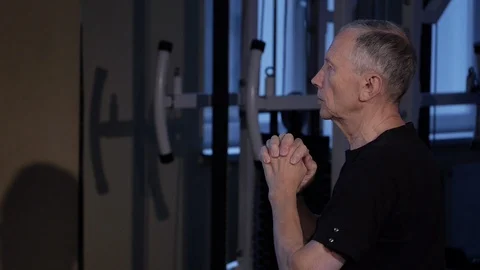A man of the age performs joint gymnastics for the elbows and back in the gym Stock Footage 115508835