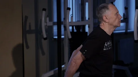 A man of the age performs joint gymnastics for the back in the gym.Straightening Stock Footage 115509454