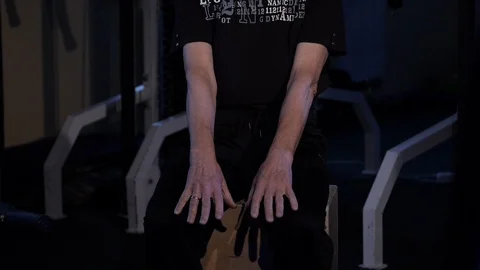 A man of the age performs joint gymnastics for the fingers in the gym.Clenching Stock Footage 115873707