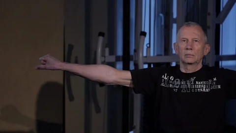 A man of the age performs joint gymnastics for the fingers in the gym.Clenching Stock Footage 115876241