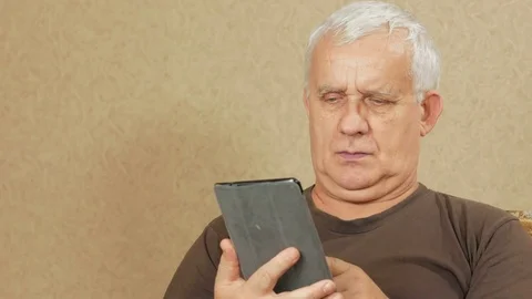 The man at the age of the tablet reads the news at home on the couch. He leafs Stock Footage 71246963