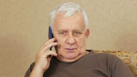 The man at the age of talking on a cell phone at home on the couch. His facial Stock Footage 71244736