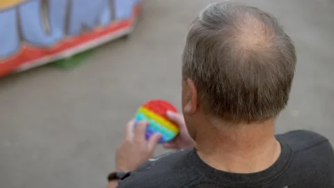 A man aged plays in a popit on the background of a public park. The person is Stock Footage 159650209