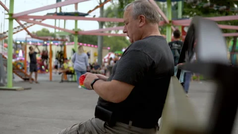A man aged plays in a popit on the background of a public park. The person is Stock Footage 159650521