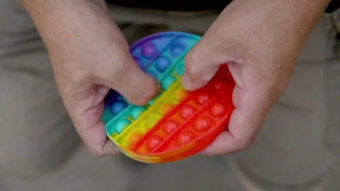 A man aged plays in a popit close-up. The person is passionate about rainbow Stock Footage 159650811