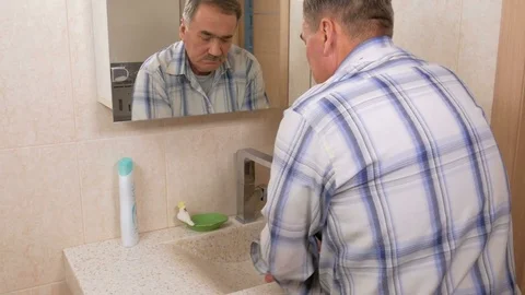 Man aged wash your face with soap in the bath. He rinses the face with water Stock Footage 70134211