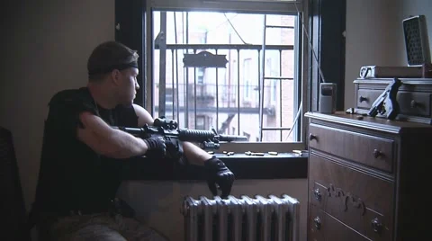 Man aiming gun out window Stockbeeldmateriaal 47688057