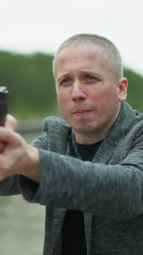Man Aiming Handgun with Determined Expression by Railway Track Stock Footage 316503621