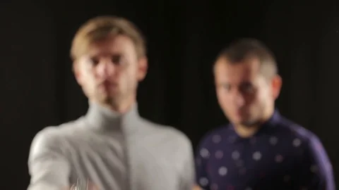 Man aims a gun at camera in focus close up blur faces portrait of two criminal Stock Footage 70283659