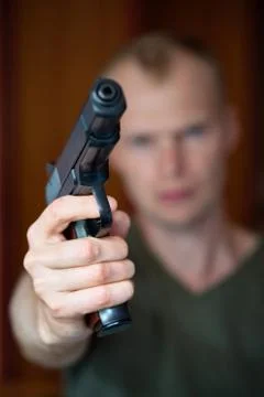 A man aims his semi automatic pistol. Selectively focused on the front of the Stock Photos