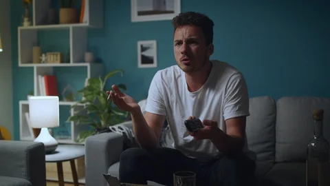 Man alcoholic drinking beer or cocktail from glass and watching tv at home Stock Footage 112977034