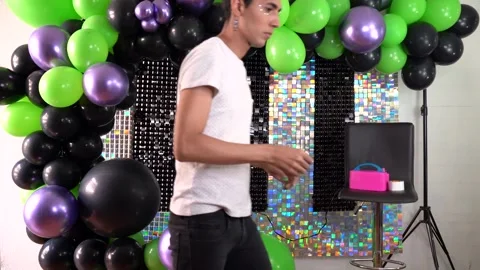 Man aligning green, black and purple balloons. Setting backdrop at event. Stage Stock Footage 303349216